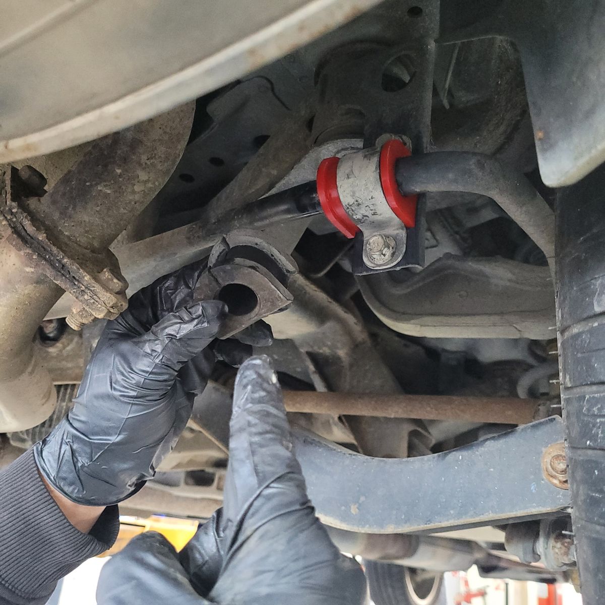 Mechanic installing new sway bar bushing under vehicle