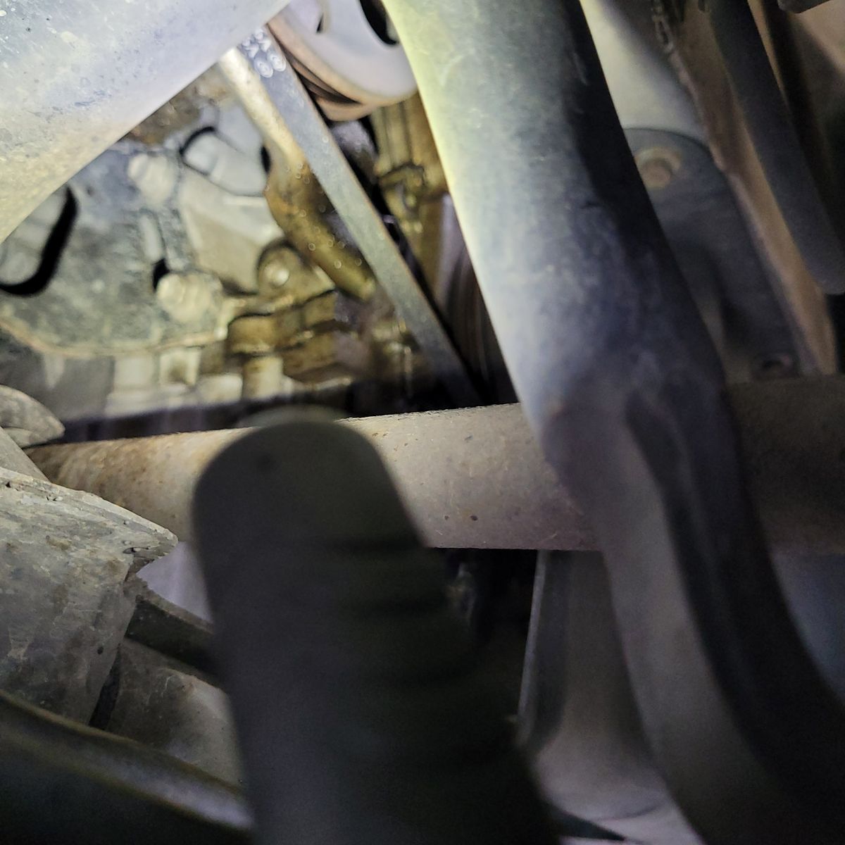 Close-up view of oil leaking from an engine timing cover area