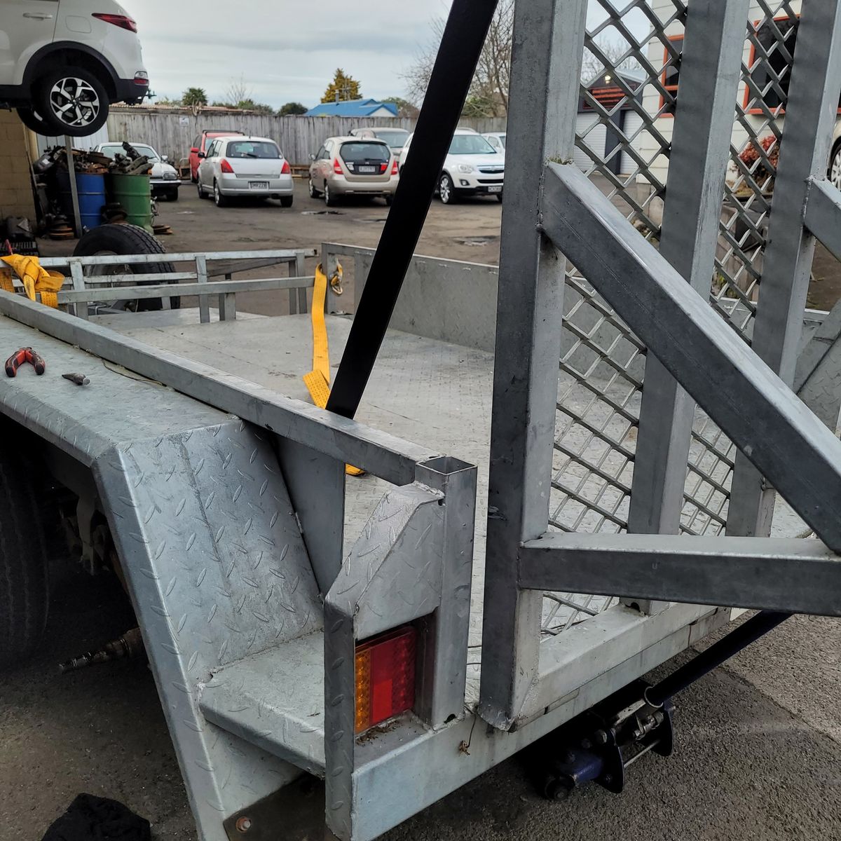 Utility Trailer Rear Gate Repair in Parking Lot Metal utility trailer with ramp gate in repair at lot