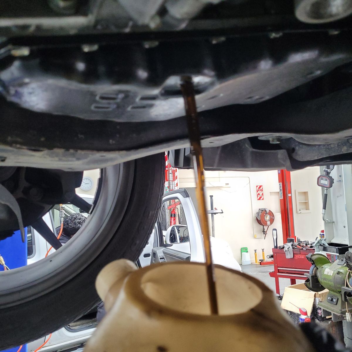 Transmission fluid draining from a car into a container in a garage