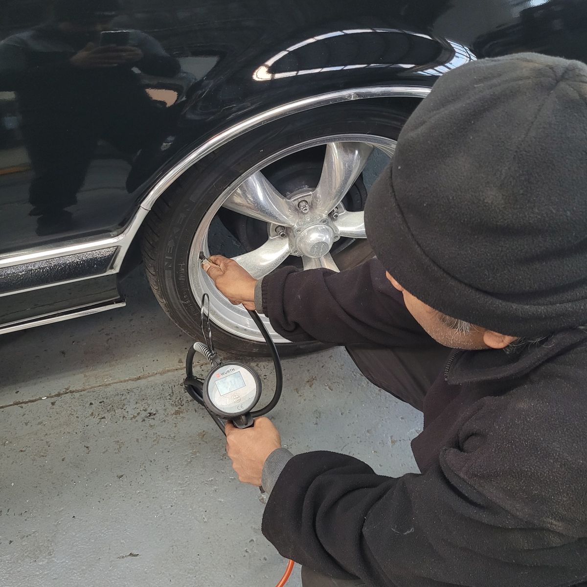 Mechanic Checking Car Tyre Pressure Person using a digital gauge to check car tyre pressure