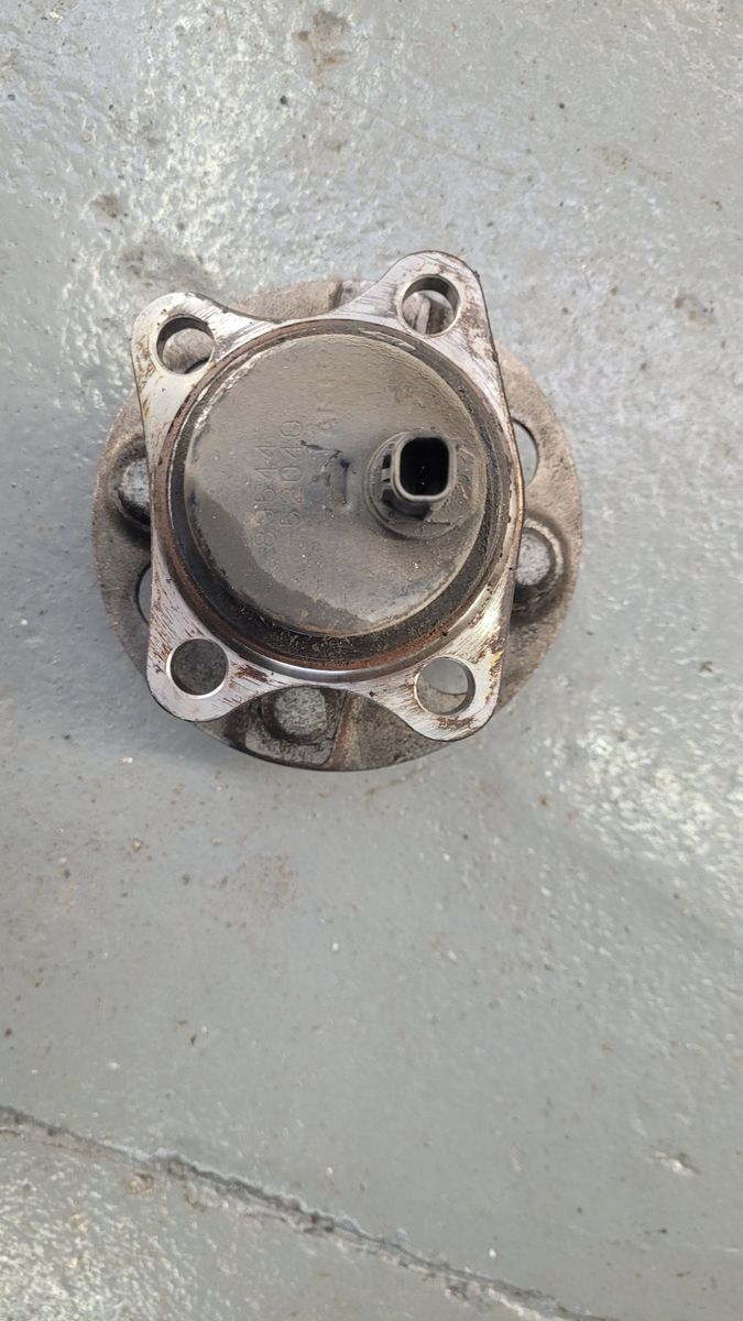 Used Automotive Wheel Bearing Hub Assembly Dirty used wheel bearing hub with connector port on gray floor